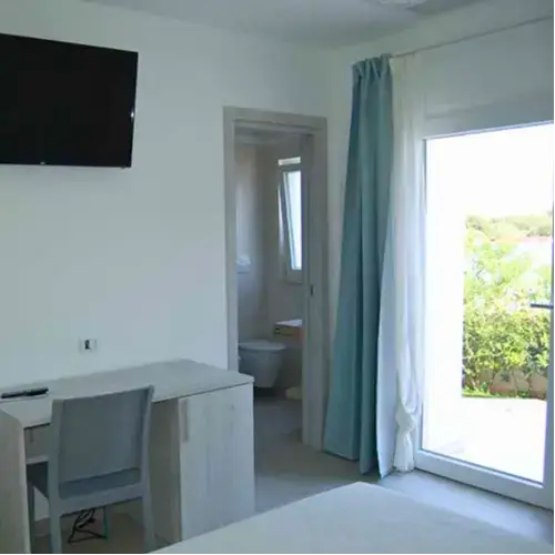 Camera matrimoniale moderna di Tenuta Verdolivo a Ostuni, arredamento minimalista bianco con tocchi di blu.